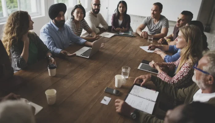 Pessoas reunidas em mesa para debater por meio de edital de convocação