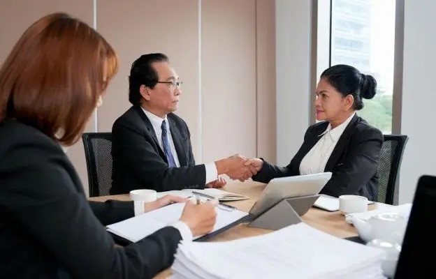 Ata de reunião empresarial durante cumprimento profissional entre executivos em sala corporativa com documentos e notebook.