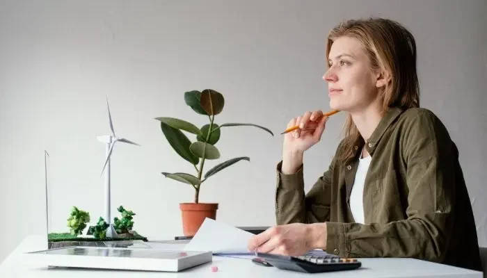 Imagem de mulher branca loira de camisa verde e de perfil com papel na mão analisando a Lei 6938.