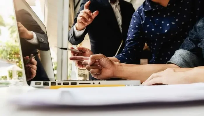 Imagem de pessoas em volta de mesa com notebook ilustrando o clipping.