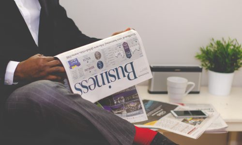 imagem representando a figura masculina segurando um jornal em um escritório lendo sobre redução de capital