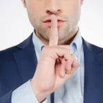 Homem com um dedo em frente a boca representando a lei do silêncio