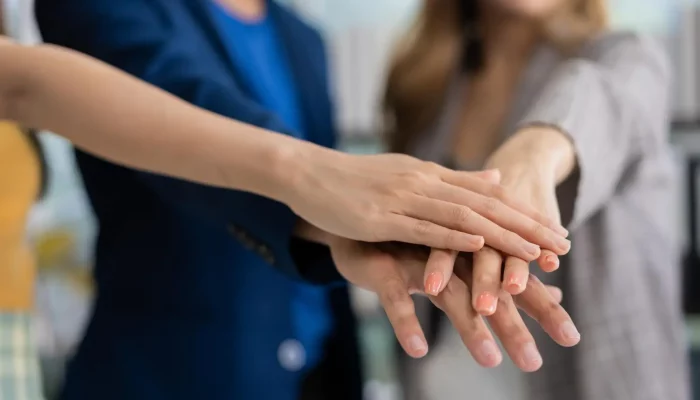 Mãos de profissionais unidas em equipe para ilustrar o que é razão social em uma empresa